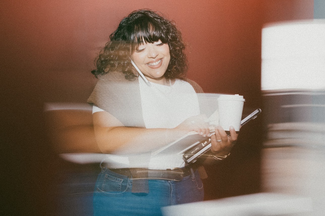 Laughing while carrying a coffee and planner